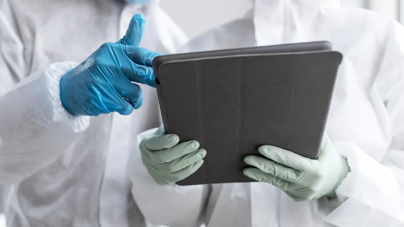 Veterinarios forenses revisando un informe pericial en una tablet, con equipo de protección y guantes.