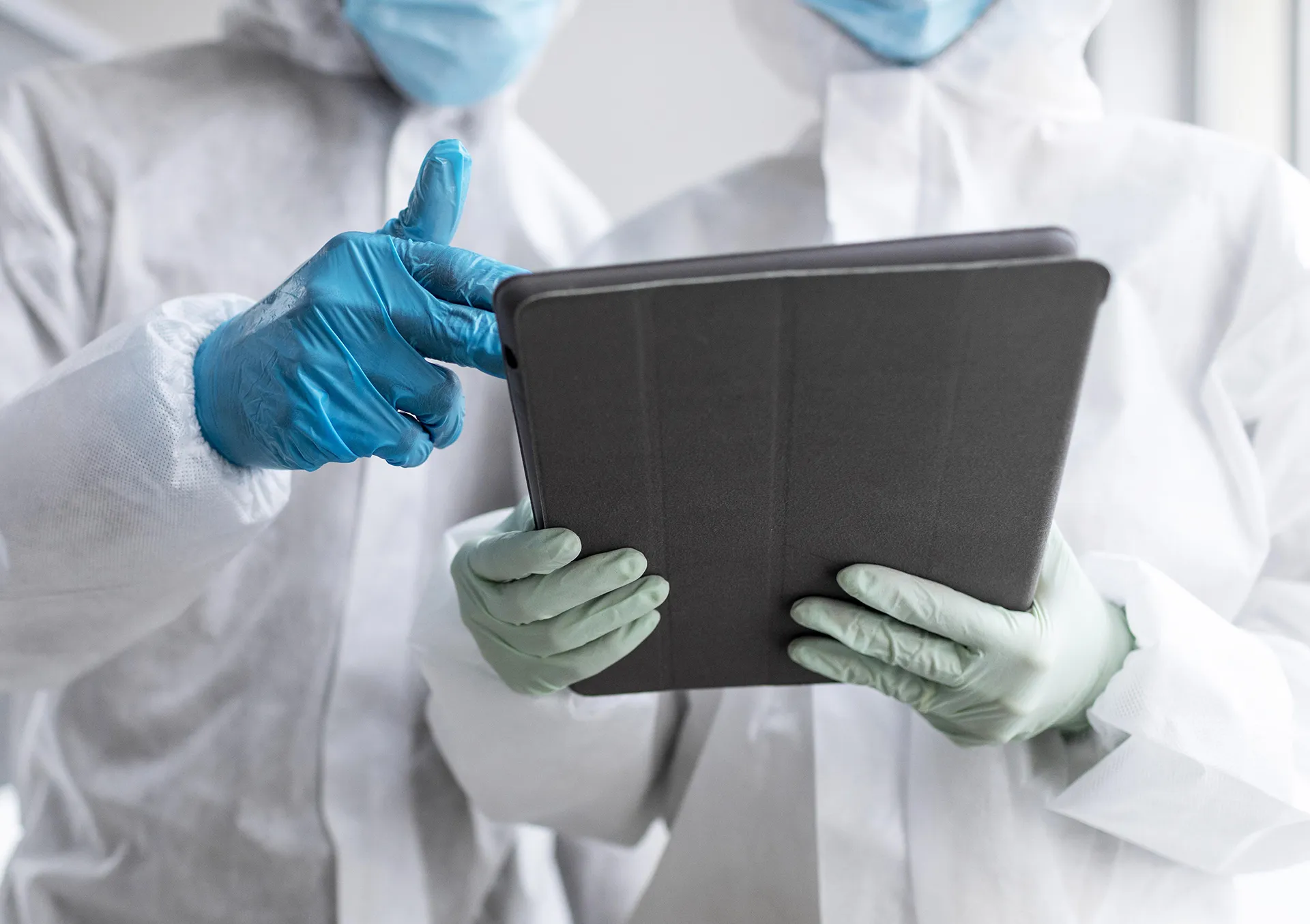 Veterinarios forenses revisando un informe pericial en una tablet, con equipo de protección y guantes.