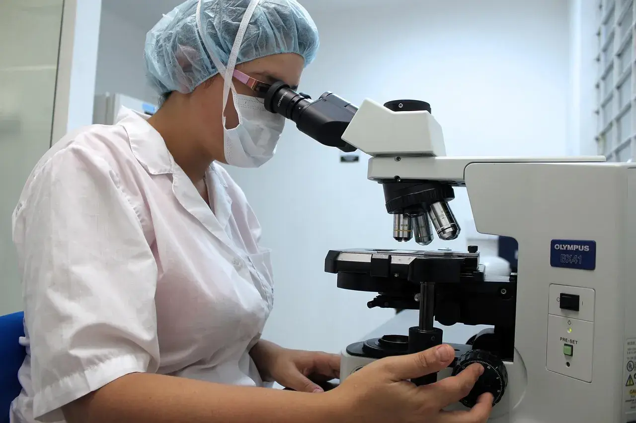 Perito veterinario usando microscopio en laboratorio para informe pericial. Crecimiento sector informes periciales veterinarios